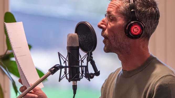 mannelijke voice-over stemacteur achter de microfoon met script in zijn hand