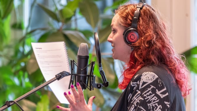 vrouwelijke stemacteur achter microfoon met script in hand